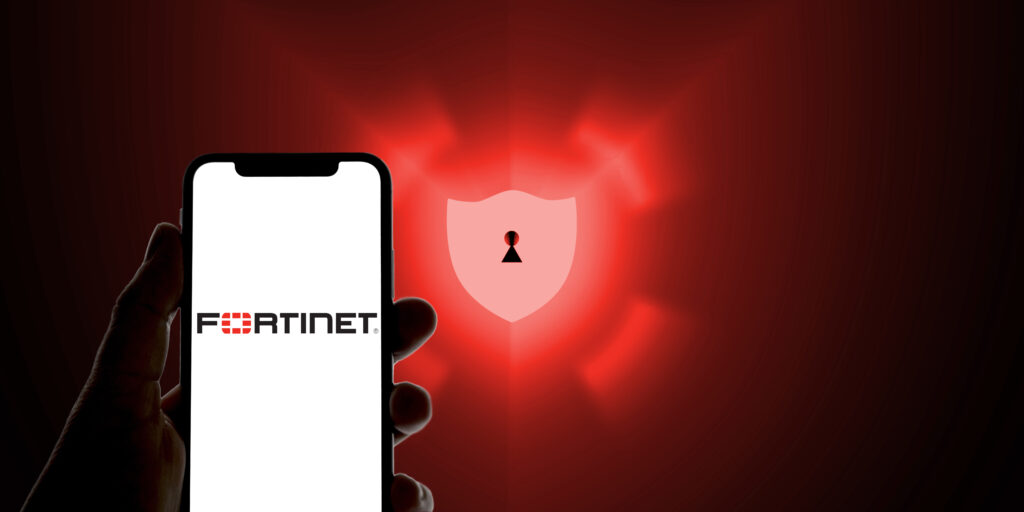 Fortinet logo on a smartphone in front of a defense shield as a symbolic image for antivirus software, anti spam, scam, malware