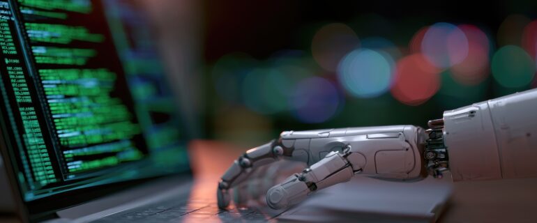 Robotic Hand Interacting with Laptop Displaying Code. A close-up shot of a robotic hand resting on a laptop keyboard, with lines of green code visible on the screen.